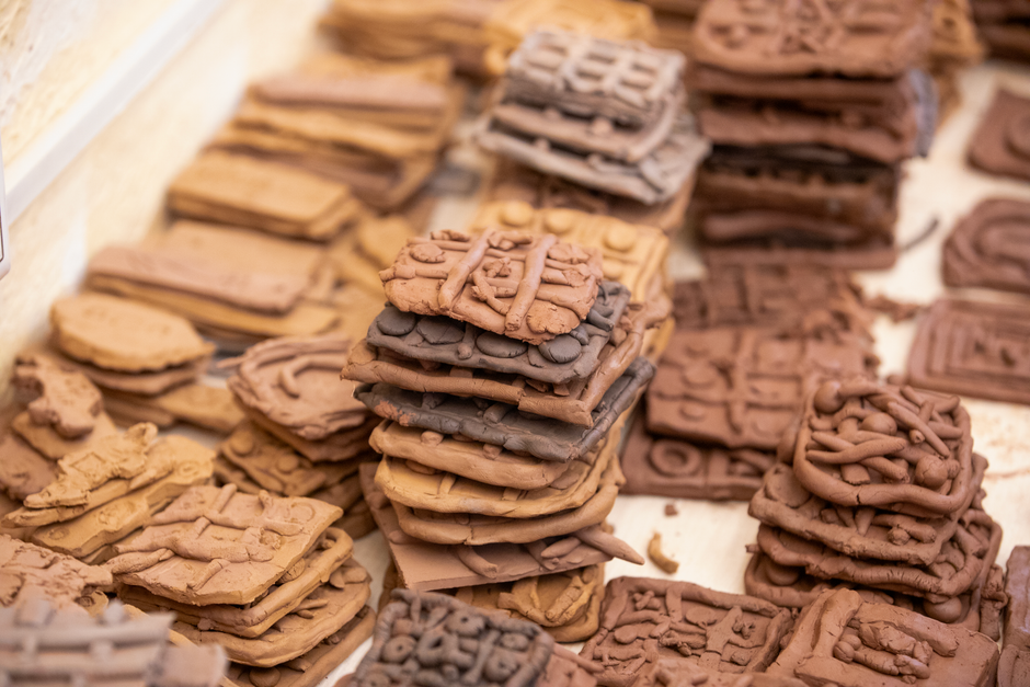 Close-up of stacked clay tablets with intricate, ancient designs in various shades of brown.
